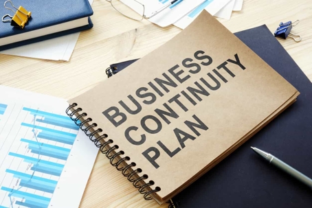 Notebook with "Business Continuity Plan" written on it.
